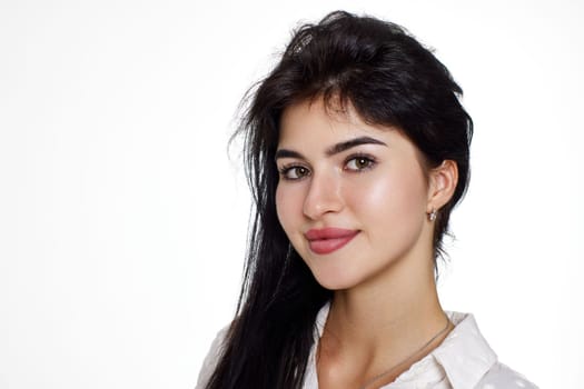 beautiful brunette young woman in a white blouse smiling on a white background