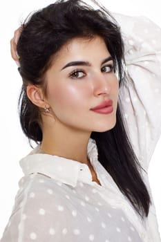 beautiful brunette young woman in a white blouse smiling on a white background