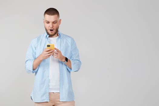 surprised handsome man with mobile cell phone surfing internet. copy space