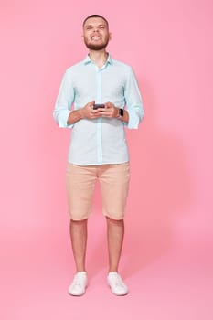 happy handsome bearded man in summer blue t-shirt messaging with mobile cell phone