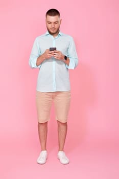 happy handsome bearded man in summer blue t-shirt messaging with mobile cell phone