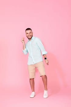 cheerful young happy man dance on pink background. vacation summer. Full body