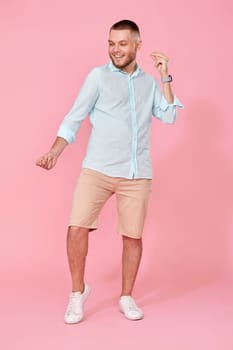 cheerful young happy man dance on pink background. vacation summer. Full body