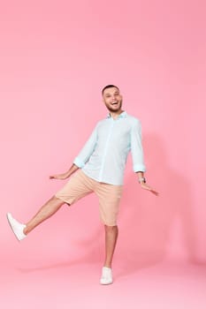 happy funny young man in casual shirt posing isolated on pink background. Having fun, fooling around