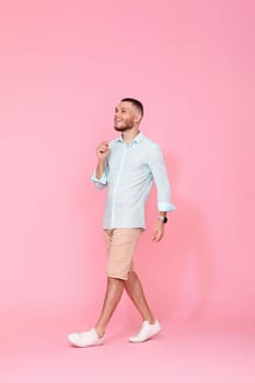 handsome happy man walks isolated on pink background. vacation summer.