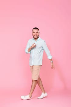 handsome happy man walks isolated on pink background. vacation summer.