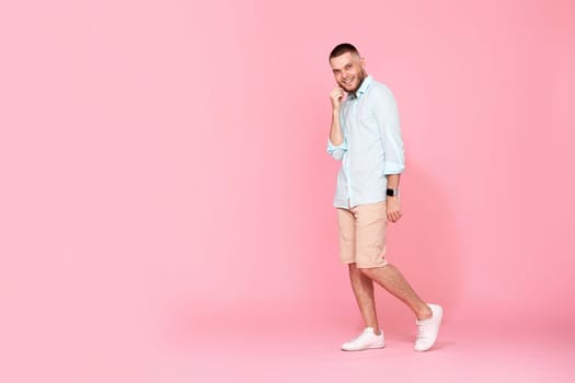 young caucasian smiling bearded man wearing casual shirt isolated on pink background. Full length