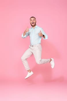 young man in summer clothes jumping isolated on pink background. Full length