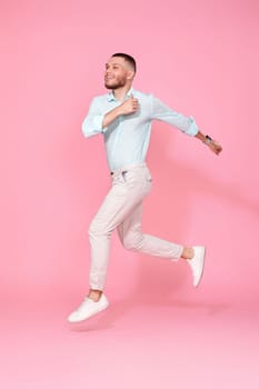 young man in summer clothes jumping isolated on pink background. Full length
