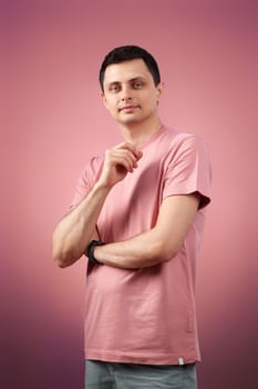 handsome man in t-shirt looking at the camera on pink background