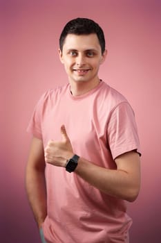brunette man in t-shirt smiling and showing ok sign isolated on pink background
