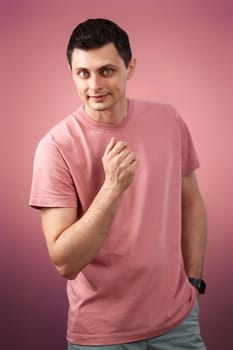 handsome man in t-shirt looking at the camera on pink background