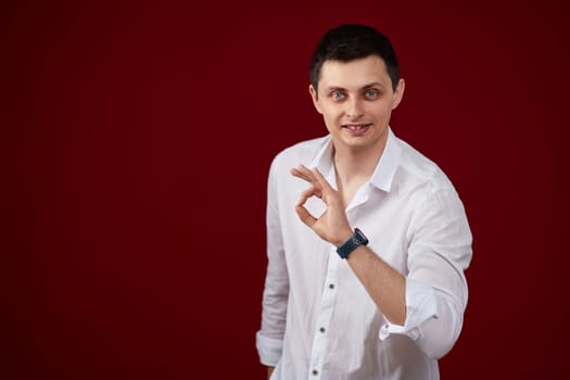 brunette man in t-shirt smiling and showing ok sign isolated on pink background