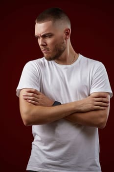 young handsome man in a white t-shirt thinks about something on a red background