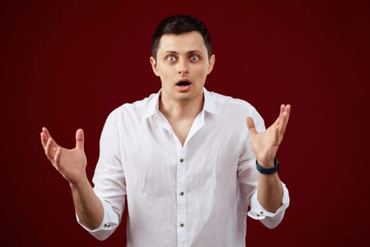 surprised shocked brunette man in white shirt isolated on red background
