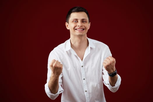 happy young man celebrating victory on red background.