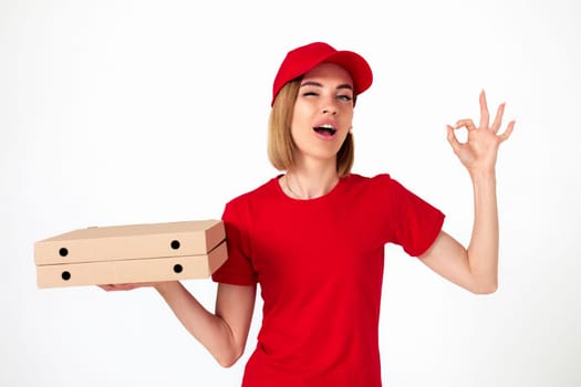 pizza delivery girl in uniform with pizza boxes showing ok gesture on white background