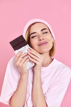 lovely pretty charming cute dreamy woman enjoying dark chocolate isolated on pastel pink background