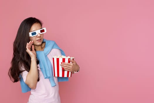 scared terrified woman watching movie film, holding bucket of popcorn on pink background. copy space