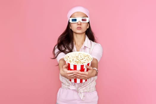 pretty woman holding bucket of popcorn isolated on pink background. focus on popcorn