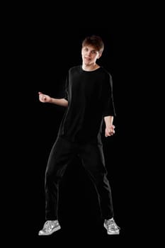 young man in black t-shirt dancing on black background. Full length