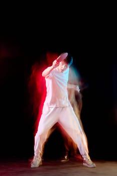young man playing table tennis in mixed neon light on dark background. Concept of motion