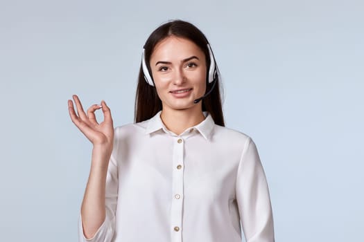 woman in headset is consulting clients online. call centre operator showing Ok gesture