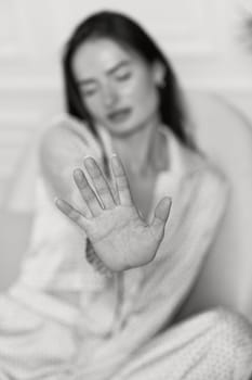 brunette woman in pajamas showing stop gesture. black and white