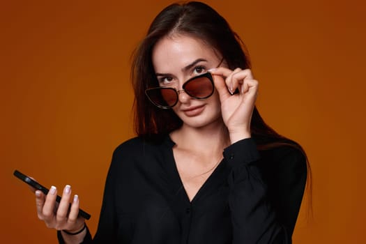 happy woman in black shirt and jeans using mobile cell phone on color background.