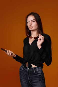 happy woman in black shirt and jeans using mobile cell phone on color background.