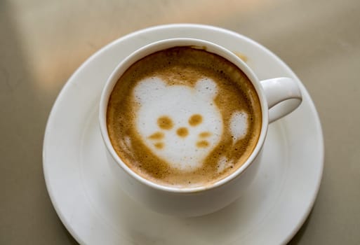 Shape of a cat or kittens face drawn in the milk foam or froth in top of cup of coffee