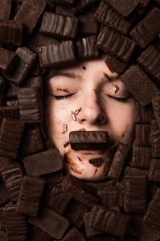 The face of a caucasian woman surrounded by sweets. The girl is smeared in sweets