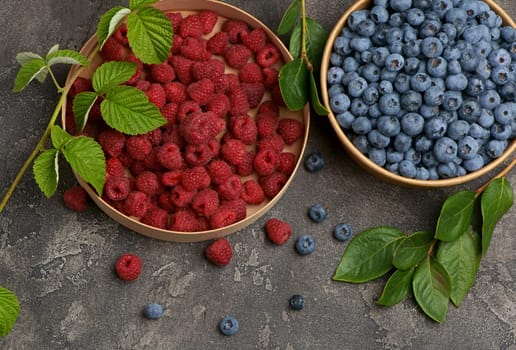 A variety of summer berries - raspberries, strawberries blueberries, - in cups on a wooden table