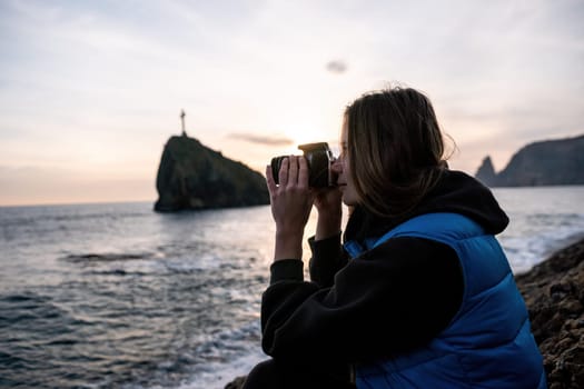 Woman travel sea. Happy tourist taking picture outdoors for memories. Woman traveler looks at the edge of the cliff on the sea bay of mountains, sharing travel adventure journey.