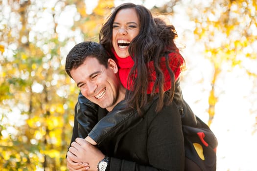 Amazing funny young couple in autumn park having fun