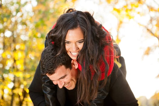 Amazing funny young couple in autumn park having fun