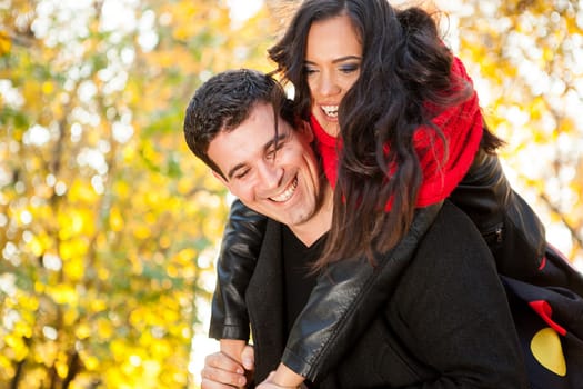 Amazing funny young couple in autumn park having fun