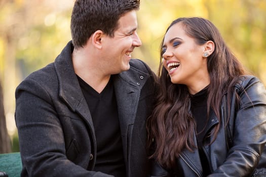 Close up of beautiful in love couple sitting on a bench in autumn park