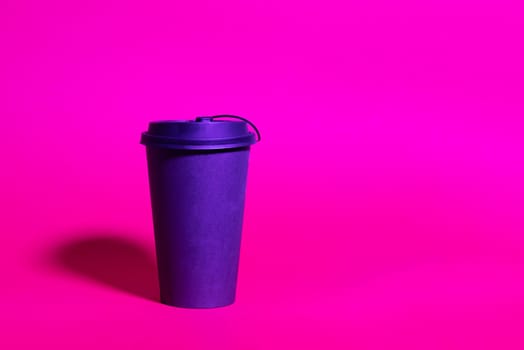 Mock up of black paper coffee cup ready to go, trend duotone neon ultraviolet color lightning. Colored light, creative trendy effect