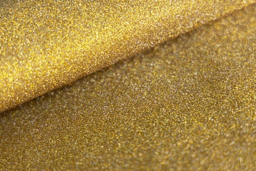 Golden wave shiny glitter paper texture. Shining luxurious fabric. Glimmering golden color, christmas background.