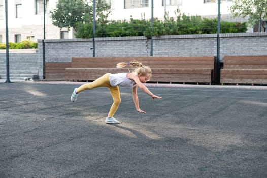 Caucasian girl makes a cartwheel on the sports field outdoors