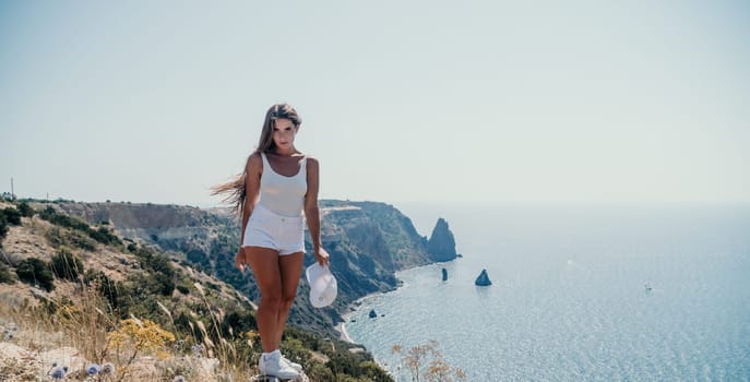 Woman travel sea. Young Happy woman in a long red dress posing on a beach near the sea on background of volcanic rocks, like in Iceland, sharing travel adventure journey