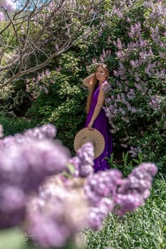 Fashion Model in Lilac Flowers, Young Woman in Beautiful Long Dress Waving on Wind, Outdoor Beauty Portrait in Blooming Garden.