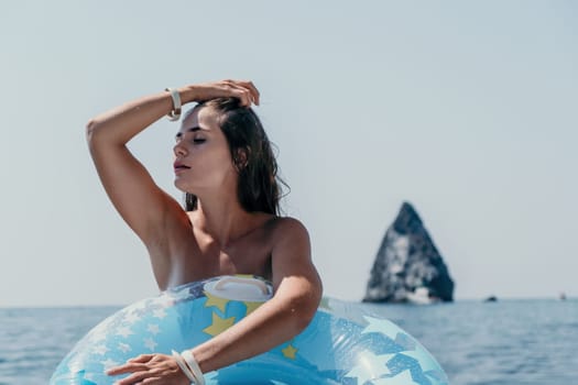 Woman summer sea. Happy woman swimming with inflatable donut on the beach in summer sunny day, surrounded by volcanic mountains. Summer vacation concept