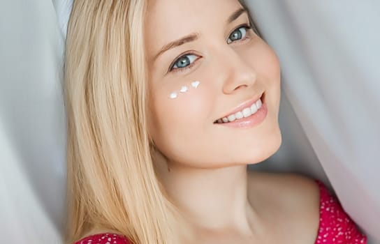 Beautiful woman with skincare cream on her face.