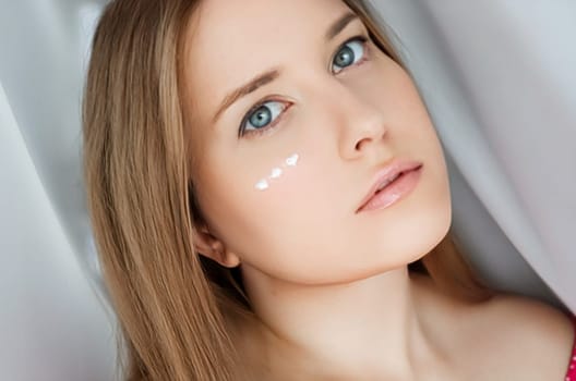 Beautiful woman with skincare cream on her face.