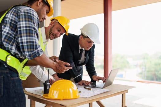 Architect team working with blueprints for architectural plan, engineer sketching a construction project, green energy concept.