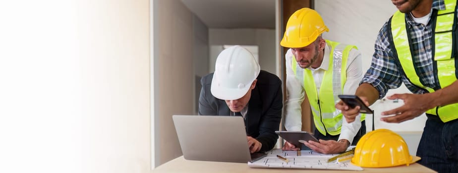 Architect team working with blueprints for architectural plan, engineer sketching a construction project, green energy concept.