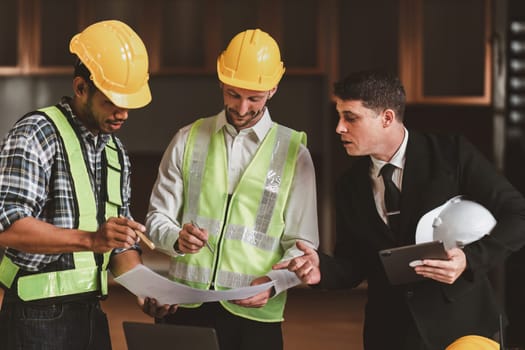 Architect team working with blueprints for architectural plan, engineer sketching a construction project, green energy concept.