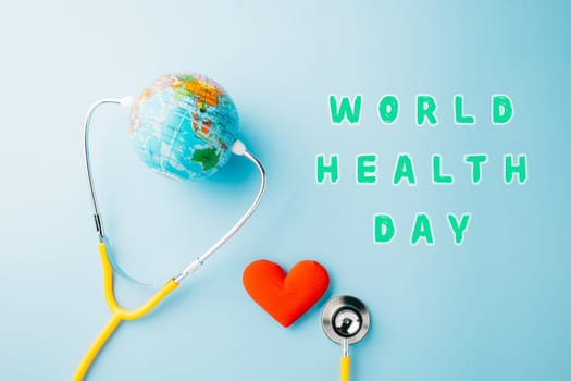 World Health Day. Yellow doctor stethoscope and world globe with Red heart shape isolated on blue background with copy space, Save world day, Green Earth Environment, Healthcare and medical concept
